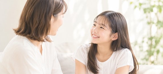 向かい合って笑顔で話す母親と娘